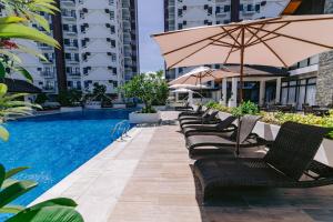 a row of chairs with umbrellas next to a pool at Royal Oceancrest Eleanor suites in Lapu Lapu City