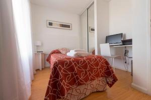 a room with a table with a bed with a blanket at Edificio Guttero in Caleta Olivia