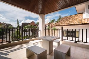 a patio with a table and benches on a balcony at Cheeva Pool Villa Phuket in Phuket