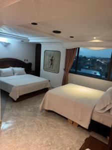 a hotel room with two beds and a window at Hotel Americas Suites in Bogotá