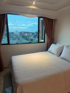 a bedroom with a large bed with a large window at Hotel Americas Suites in Bogotá