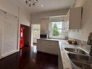 a white kitchen with a sink and a red refrigerator at Central Chatswood Urban Stay in Sydney