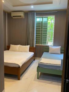two beds sitting in a room with a window at NHÀ KHÁCH KEN in Cà Mau