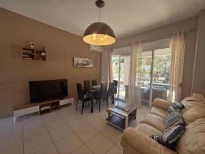 a living room with a couch and a television and a table at Casa Fountain Villa in Kolymbia