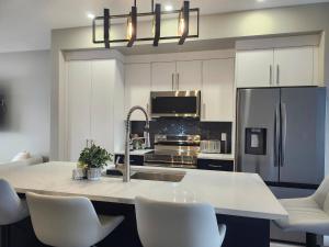 a kitchen with white cabinets and a kitchen island with white chairs at Harmony Haven in Drumheller in Drumheller