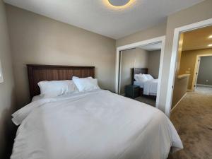 a bedroom with a large white bed and a mirror at Harmony Haven in Drumheller in Drumheller