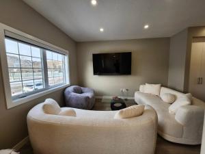 a living room with two couches and a flat screen tv at Harmony Haven in Drumheller in Drumheller