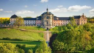 a large building on a hill next to a river at Jurty u jezírka in Mostek
