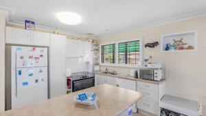 a kitchen with white cabinets and a white refrigerator at Driftwood At Beachmere in Beachmere