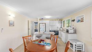 a kitchen with a wooden table and chairs at Driftwood At Beachmere in Beachmere +14 photos