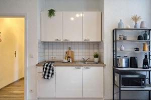 a kitchen with white cabinets and a sink at N&N City Apartment Schwerin mit Parkplatz in Schwerin +10 photos