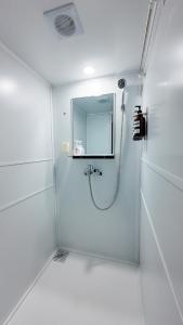 a white bathroom with a shower with a mirror at 지하철 2분, 침대3, 4인 최적, 5인 가능, 홍대 경복궁 명동 동대문 이동편리 in Samgong +60 photos