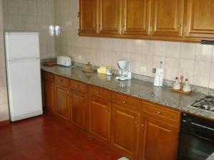 een keuken met houten kasten en een witte koelkast bij Casa da Benda in Caniçada