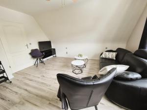 a living room with a black couch and chairs at Nordlandgiebel in Rosengarten