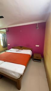 a bedroom with two beds and a purple wall at Anand Comfort in Anakāpalle
