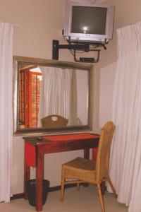 een bureau met een spiegel en een tv aan de muur bij African Aquila Guest Lodge in Port Elizabeth