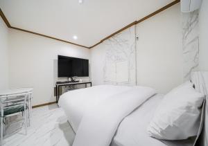 a white bedroom with a bed and a television at Hasen Hotel in Siheung