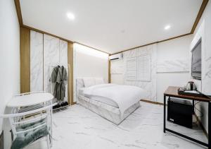 a white bedroom with a bed and a tv at Hasen Hotel in Siheung