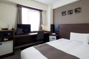 a hotel room with a bed and a desk with a computer at Comfort Hotel Sakai in Sakai