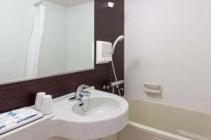 a bathroom with a sink and a mirror and a tub at Comfort Hotel Tokyo Kanda in Tokyo +25 photos
