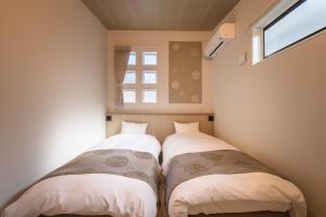 two beds in a small room with a window at TEMARI Premier NORTH in Hakone