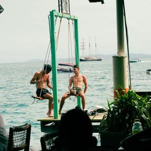 two men sitting on a dock in the water at Klika Bocas del Toro in Bocas Town