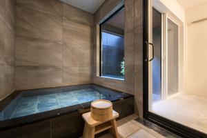 a bathroom with a tub with a stool and a window at TEMARI Premier NORTH in Hakone