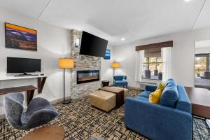 a living room with blue furniture and a fireplace at Clarion Pointe I-85 High Point - Archdale in Westwood