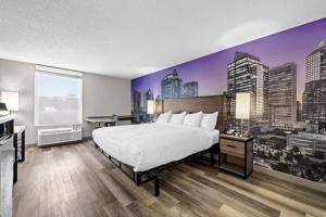 a hotel room with a bed and a city skyline mural at Clarion Pointe I-85 High Point - Archdale in Westwood +25 photos