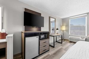 a hotel room with a television and a kitchen with a bed at Clarion Pointe I-85 High Point - Archdale in Westwood