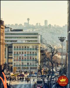 a busy city street with a large building and pedestrians at Tac Hotel in Ankara
