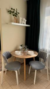a wooden table with two chairs and a table with plates at Апартаменти GREEN центр вулиця Руська in Ternopil +9 photos