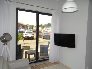a living room with a tv and a sliding glass door at Apartament Portowy w Ustce in Ustka