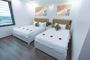 two beds in a room with white walls at Anna Noi Bai Airport Hotel in Sóc Sơn