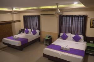 two beds in a room with purple pillows at Hotel UR Comforts Jayanagar in Bangalore