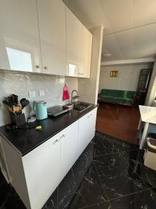 a kitchen with white cabinets and a black counter top at Mini apartment in Central UB in Ulaanbaatar