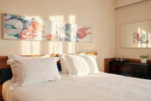 a bedroom with a bed with white sheets and pillows at AQUAMARE CITY and BEACH in Rhodes Town +41 photos