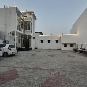 a white building with a car parked in front of it at Sri Ram Shankar-Saryu Ghat in Ayodhya