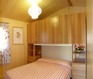 a small bedroom with a bed and wooden cabinets at Ca' Berton Village in Cavallino-Treporti +163 photos