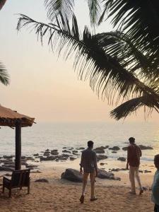 two men standing on a beach looking at the ocean at Calangute Beach Prime in Calangute