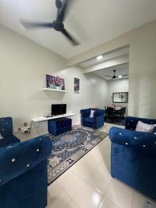 a living room with blue chairs and a ceiling fan at Teratak Amaris Homestay MELAYU ONLY in Sungai Petani