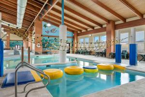 a swimming pool with yellow and blue stools in a building at Big Horn Resort, an Ascend Collection Hotel in Billings
