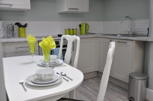 a white kitchen with a white table and chairs at Bove Town House Apartments in Glastonbury
