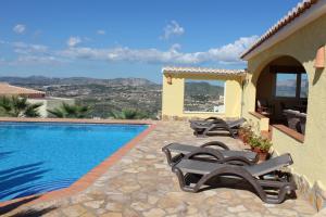 une villa avec une piscine et deux chaises longues dans l'établissement Amarilla, à Cumbre del Sol
