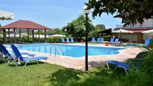 a swimming pool with blue chairs and a light pole at Denis Hotel and Bungalows in Korinos