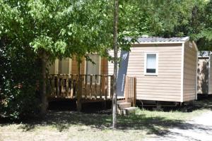 a small house with a wooden fence and a tree at Lodge in Joyeuse