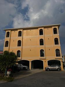 a yellow building with a car parked in front of it at Natcha Hotel and Residence in Sathani Chumphon
