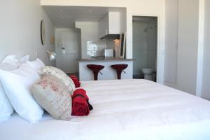 a white bed with red blankets and pillows on it at Blouberg Studio Wow in Bloubergstrand