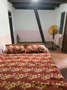 a bedroom with a bed with a red comforter at RR Homestay in Nīleswaram