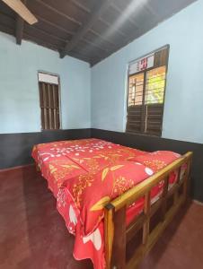 a bedroom with a wooden bed with a red blanket at RR Homestay in Nīleswaram